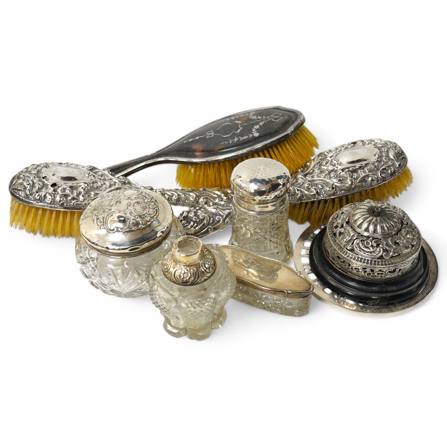 A late Victorian pierced silver mounted table bell (a.f.), London, 1900, together with two silver mounted hair brushes (a.f.), a silver and tortoiseshell pique mounted hairbrush, four assorted silver mounted glass toilet